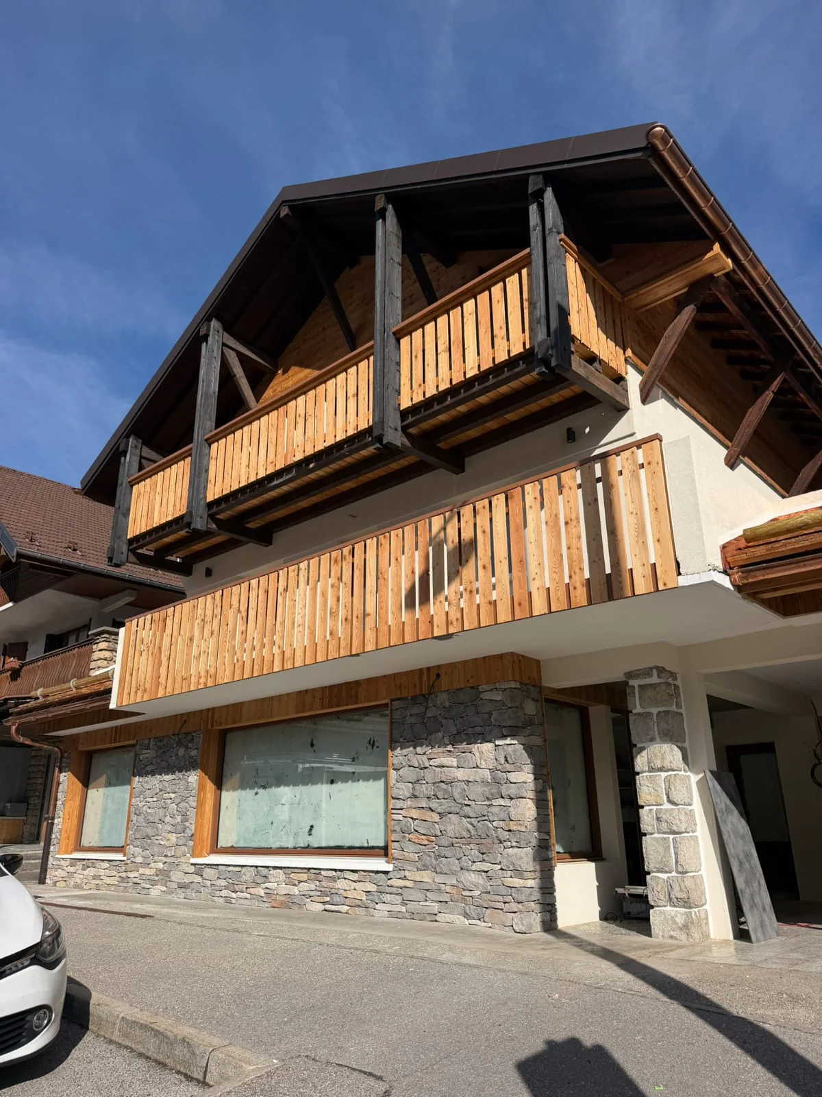 Façade de chalet avec soubassement en parement pierre et balcons en bois