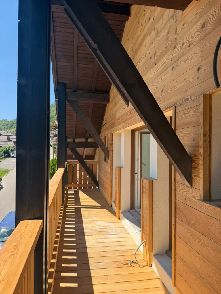 Façade habillée de lames de bois horizontales, coursive et garde-corps en bois