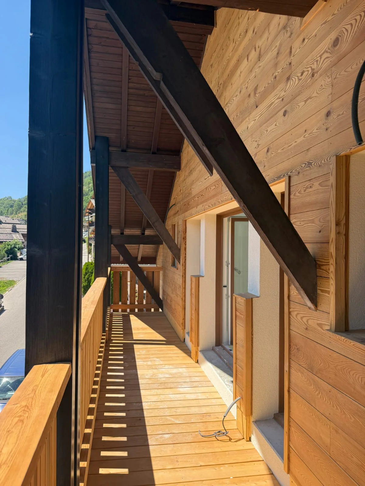 Façade habillée de lames de bois horizontales, coursive et garde-corps en bois