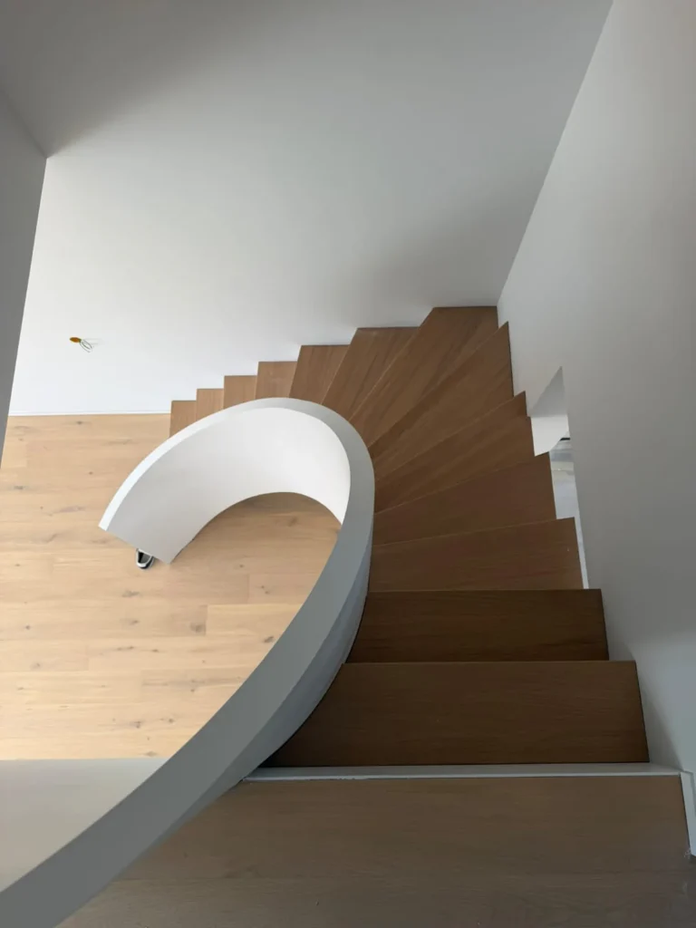Escalier aux marches en bois clair et au limon blanc courbe