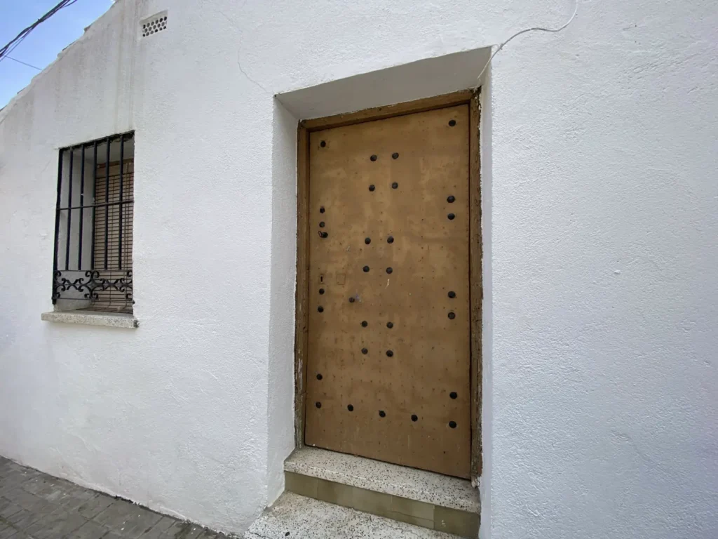 Mur enduit blanc percé d’une porte en bois