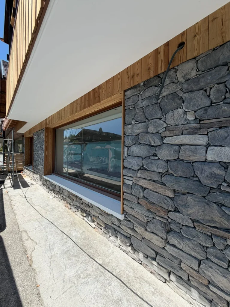 Parement pierre autour d’une grande baie encadrée de bois