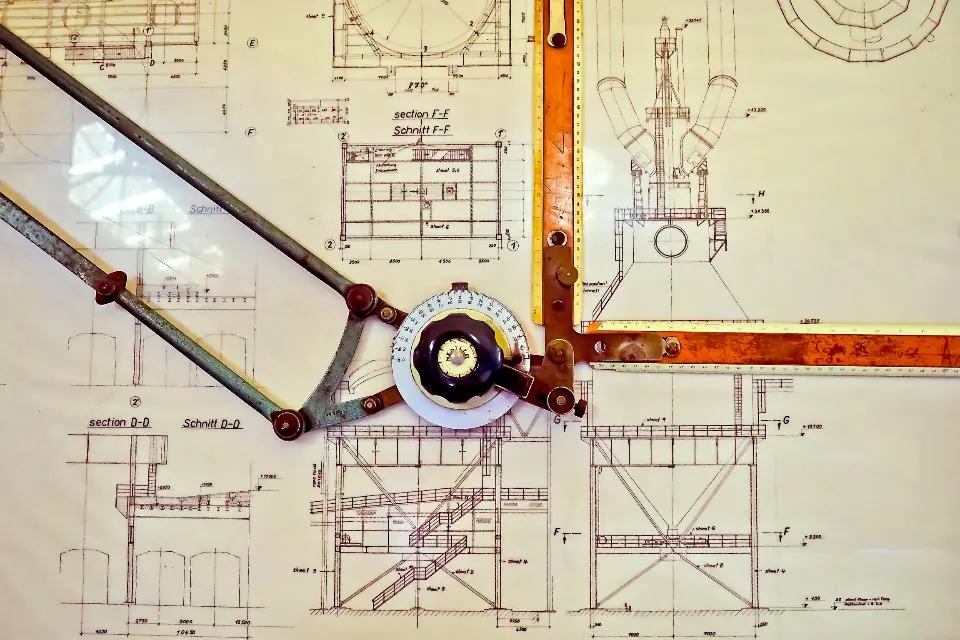 Plans, équerre et compas posés sur une table de travail