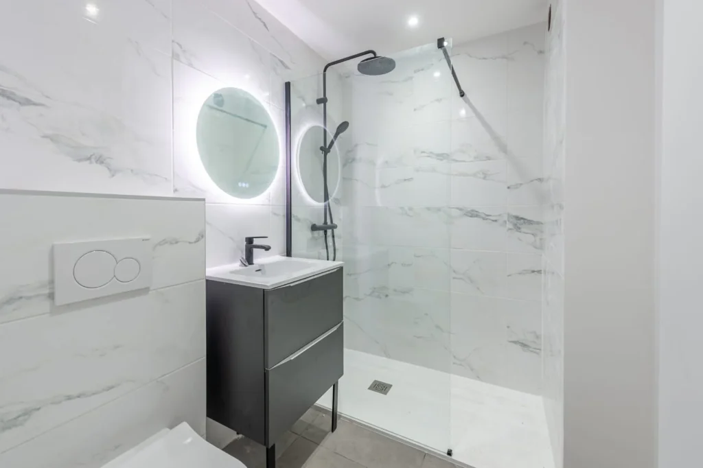 Salle d’eau à la faïence effet marbre, douche vitrée et meuble vasque suspendu